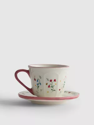 Taza de café con plato y decoración de flores